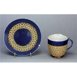 A Doulton Lambeth stoneware cup and saucer, applied with graduated rows of florets picked out in pal