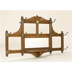 A late 19th Century oak and brass wall-mounted hat rack, resembling a trellis with fluted bands and.