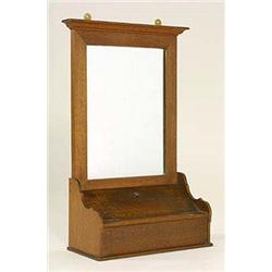An Arts and Crafts oak wall mounted shaving mirror, with projecting top, rectangular glass and conta