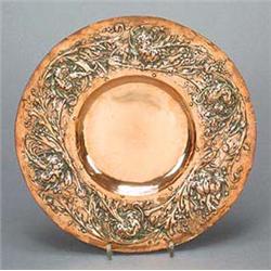 An Arts and Crafts cast copper circular wall plaque, embellished on the broad rim with stylised carn