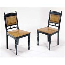 A pair of late 19th century ebonised and oak chairs, each having an ebonised shaped back rail and up