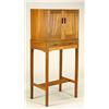 A 'Cotswold School' teak cabinet on stand, the plain top and sides having twin doors with carved bar