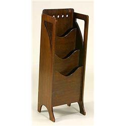 A 'Glasgow School' dark stained oak magazine rack, the plain rectangular back pierced with circular.