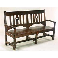 An Arts and Crafts dark oak settle, retailed through Liberty & Co., the back having a broad top rail