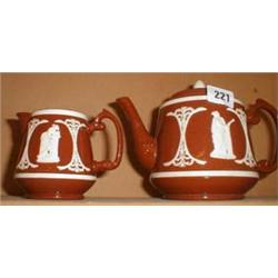 An early C20th terracotta teapot and jug with cream relief decoration