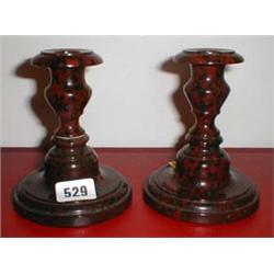 A pair of red serpentine turned candle sticks