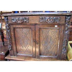 A carved Oak cupboard, one long drawer above a two panel door base.