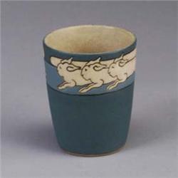 S.E.G. cup decorated with a band of rabbits at rim, all on a blue-gray ground. Marked S.E.G. 4" x 3