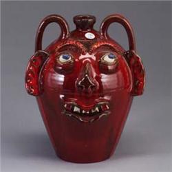 A.V. SMITH face jug covered in a candy apple red glaze, with bulging blue eyes. Signed AV SMITH. 11