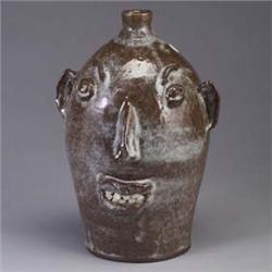 LOUIS BROWN face jug, Arden N.C., covered in a mottled umber and ivory glaze. Incised Brown's Potter