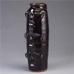 WALTER FLEMING three face totem jar with handle, covered in a mottled dark brown glossy glaze. Stamp