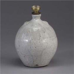 JUGTOWN bulbous lamp base covered in a flowing white semi-matte glaze over a dark body. Circular sta