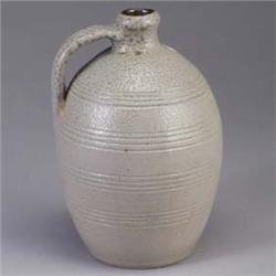 Fine BEN OWEN salt-glazed jug with incised ribs, covered in a buff glaze. Circular stamp mark. 11" x