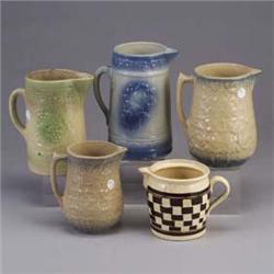 Five pitchers, four embossed with fruit or floral decoration, the fifth with checkerboard pattern (f