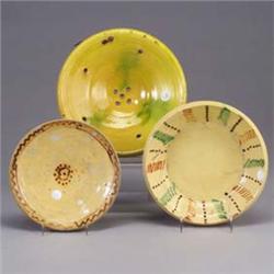 Three French pieces; a wall hanging plate in mottled green and yellow glaze, and two slipware decora