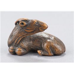 A wood netsuke of a recumbent goat.