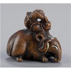 A wood netsuke of an acrobat on a Baku.