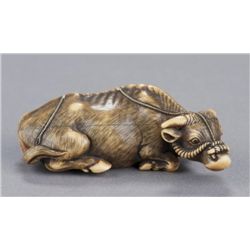 An ivory netsuke of a recumbent bull.