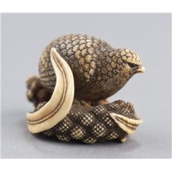 An ivory netsuke of a quail perched on millet seed