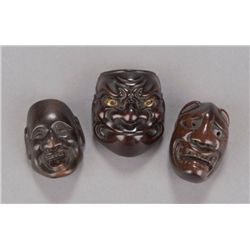 A group of three wood netsuke of masks.