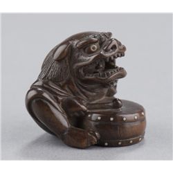 A wood netsuke of a boy wearing a Shishi mask.