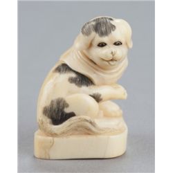 A narwhal ivory netsuke of a Piebald pup.