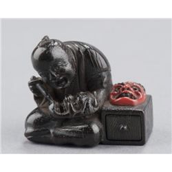 A wood netsuke of a mask masker.