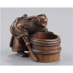 A wood netsuke of Shoki looking down well.