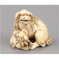 An ivory netsuke of a Shishi with young.
