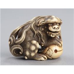 An ivory netsuke of a Shishi and a mokugyo.