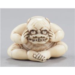 An ivory netsuke of a boy with a mask.