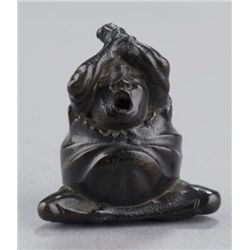 A kaki wood netsuke of Daruma yawning.