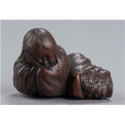 A wood netsuke of a Shojo sleeping.