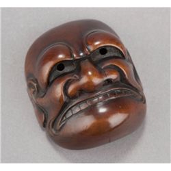 A wood netsuke of a  Buaku mask.