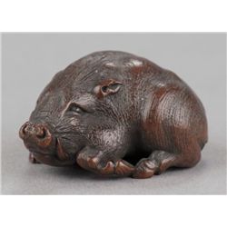A fine wood netsuke of a reclining boar.