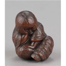 A wood netsuke of sleeping Shojo.