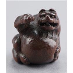 A wood netsuke of a tanuki.