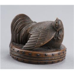 A wood netsuke of a rooster on drum.