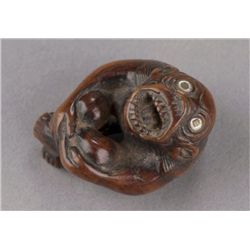A wood netsuke of a monkey with nacre eyes.