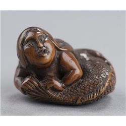 A wood netsuke of a ningyo.