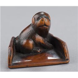A wood netsuke of a puppy.