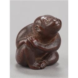A wood netsuke of a monkey.