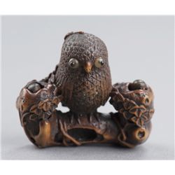 A wood netsuke of an owl and two owlets.