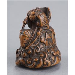 A wood netsuke of a war lord on waves.