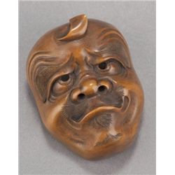 A hida pine netsuke of a Kamifuki mask.