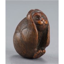 A wood netsuke of the hear no evil monkey.