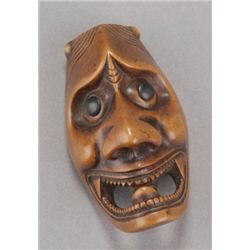 A wood netsuke of a Hannya mask.