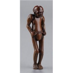 A wood netsuke of a man tying his loin cloth.
