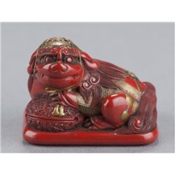 A tsuishu lacquer netsuke of a Shishi.