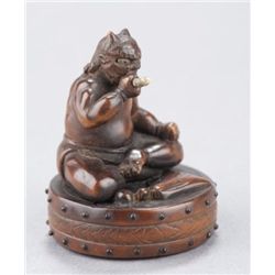 A wood netsuke of Oni on drum.